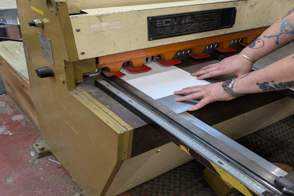 Sheet metal panel being trimmed on a guillotine cutting machine at KraftMetals.